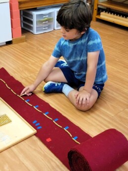 Lyonsgate Montessori student working with the Montessori 100-Chain material.