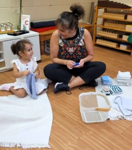 Lyonsgate Montessori Casa student learning to fold cloths during the first week of school.