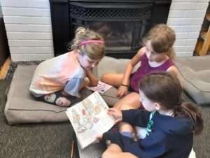 Older Montessori student reading to younger students.