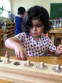 Lyonsgate Montessori student using the Montessori Cylinder Blocks material.