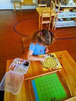 Lyonsgate Montessori Casa student placing objects in a spiral for coordination and pattern recognition.