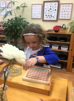 Montessori student using rubber bands material as a creative outlet and to develop hand and finger strength.