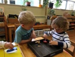 Lyonsgate Montessori students using spinning tops and Metal Insets to develop their pincer grip, hand strength, and dexterity.