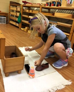 Lyonsgate Montessori student using a classic Montessori polishing material to learn sequencing of steps when performing a task.