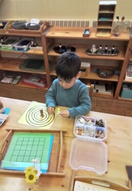 Lyonsgate Montessori student placing objects to develop hand-eye coordination.