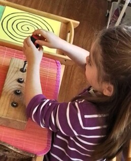 Lyonsgate Montessori student learning to use a screwdriver and developing hand strength and agility in preparation for writing.