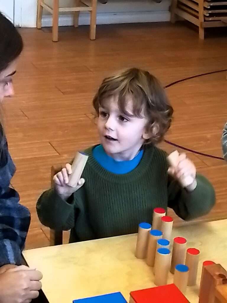 Lyonsgate Montessori student using the Sound Cylinders to develop auditory discrimination.
