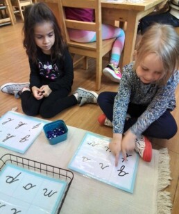 Lyonsgate Montessori students playing a sound bingo game to recognize cursive letters and their sounds.