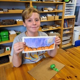 Lyonsgate Montessori elementary student and his watercolour painting of a pumpkin patch.