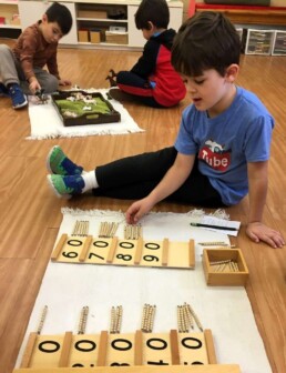 Lyonsgate Montessori student using the Golden Beads material for a visual representation of the decimal system.