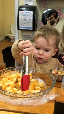 Lyonsgate Montessori student serving himself a cheese snack.