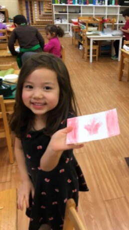 Lyonsgate Montessori Casa student with a Canadian flag she made.