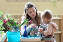 Lyonsgate Montessori toddler student filling vases with water.