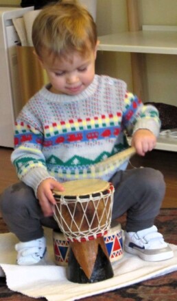 Lyonsgate Montessori Toddler student playing the drum.