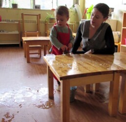 Lyonsgate Montessori Toddler student scrubbing a table, and admiring a spill.