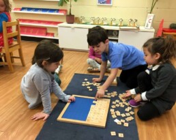Lyonsgate Montessori students receiving help from an older peer.