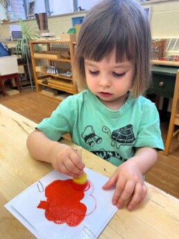 Lyonsgate Montessori student painting a poppy for Remembrance Day.