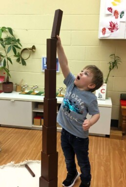 Lyonsgate Montessori Casa student building a tower as extension work with the Montessori Brown Stairs material.