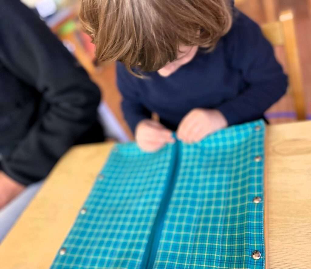 Lyonsgate Montessori Casa student practicing zipping with a Dressing Frame material.