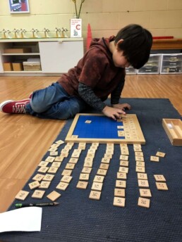 Lyonsgate Montessori Casa student working on sorting numbers to 100.