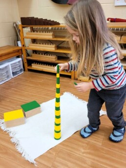 Lyonsgate Montessori Casa student building a tower with the Knobless Cylinders material.