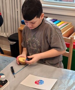 Lyonsgate Montessori Elementary student carving a potato for relief printing.