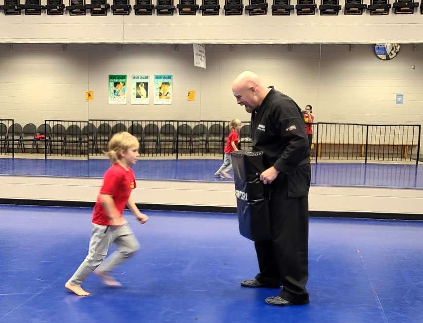 Lyonsgate Montessori Elementary student kicking the shield during martial arts phys. ed.