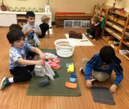 Lyonsgate Montessori Casa students folding the clean classroom cloths together.