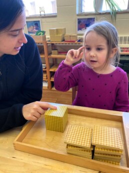 Lyonsgate Montessori Casa student thinking hard about the Montessori Golden Beads material.