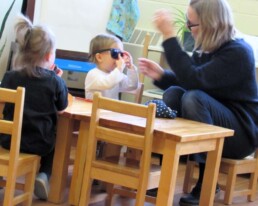 Lyonsgate Montessori Toddler student trying on sunglasses she found in the Mystery Bag.
