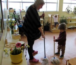 Lyonsgate Montessori Toddler student meeting with a teacher to discuss mopping strategies.