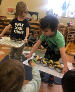 Lyonsgate Montessori Casa students serving a snack to their friends.