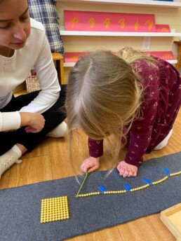 Lyonsgate Montessori Casa student working on counting to 100 with the visual representation of the Montessori 100 Chain material.