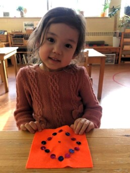 Lyonsgate Montessori Casa student sewing sequins for practical life skill and fine motor development.