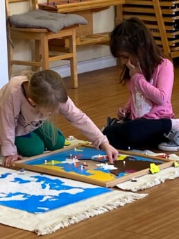 Lyonsgate Montessori Casa students learning the continents with a Montessori Puzzle Map.