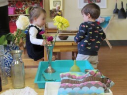 Lyonsgate Montessori Toddler students working amongst the classroom flowers.