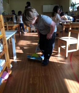 Lyonsgate Montessori Casa student mopping the classroom floor.
