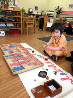 Lyonsgate Montessori Casa student working with the Montessori Moveable Alphabet material.