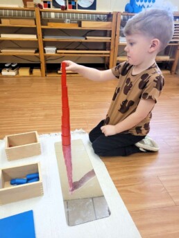 Lyonsgate Montessori Casa student building a mirrored tower with the Montessori Knobless Cylinders material.