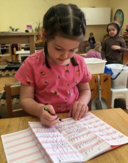 Lyonsgate Montessori Casa student practicing writing cursive letters.