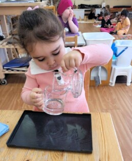 Lyonsgate Montessori Casa student developing motor skills and focus with a pouring activity.