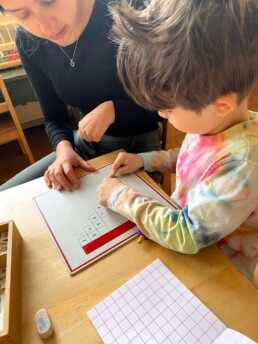 Lyonsgate Montessori Casa student working with an Addition Work Chart.