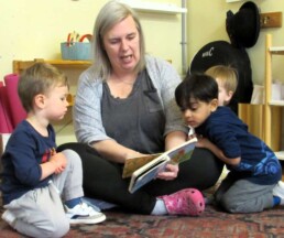 Lyonsgate Montessori Toddler students reading with their teacher.