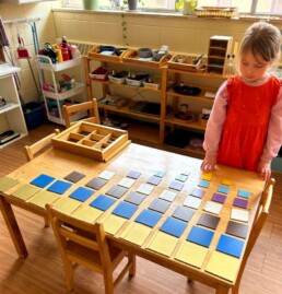 Lyonsgate Montessori Casa student working with the Montessori Decanomial Square material.