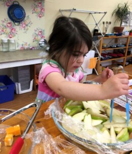 Lyonsgate Montessori Casa student eagerly helping herself to a snack; growing bodies and brains need lots of fuel.