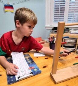 First Year Lyonsgate Montessori School Elementary student working on addition on the Montessori Bead Frame material.