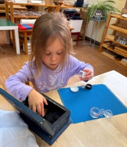 Lyonsgate Montessori School Casa student working with Boxes and Bottles activity to develop motor skills and dexterity.