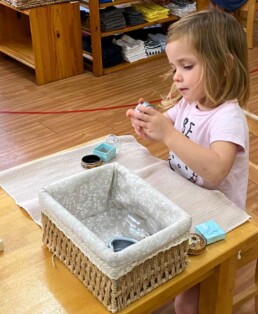 Lyonsgate Montessori School Casa student working with the Boxes and Bottles activity to develop motor skills and concentration.