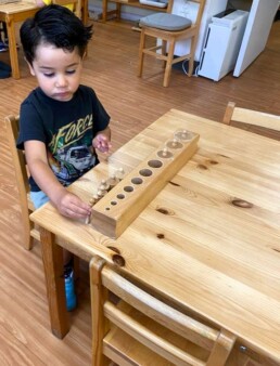 Lyonsgate Montessori School Casa student working with the Montessori Cylinder Clocks material.