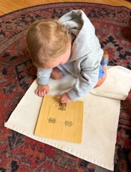 Lyonsgate Montessori School Toddler student working with the Montessori Locks and Latches material to develop fine motor skills.